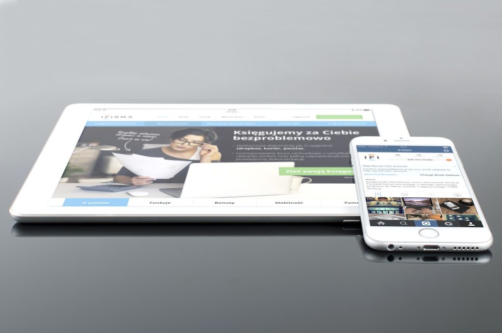 Modern tablet and smartphone displaying web content on a reflective surface, highlighting technology and connectivity.