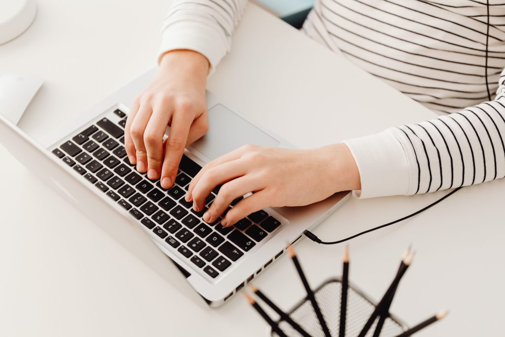 Cropped view of hands on a laptop keyboard, emphasizing digital work and technology.